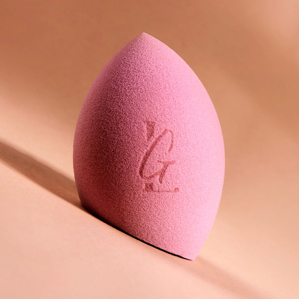 An extreme close-up of the 'Blend n Snatch' beauty sponge, resting tilted on it's angled flat bottom, so that the 'LG'  imprinted on the sponge appears exactly vertical. 