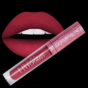 A sample bottle of the Disco Diva liquid lippie, in front of a pair of lips with the shade applied
