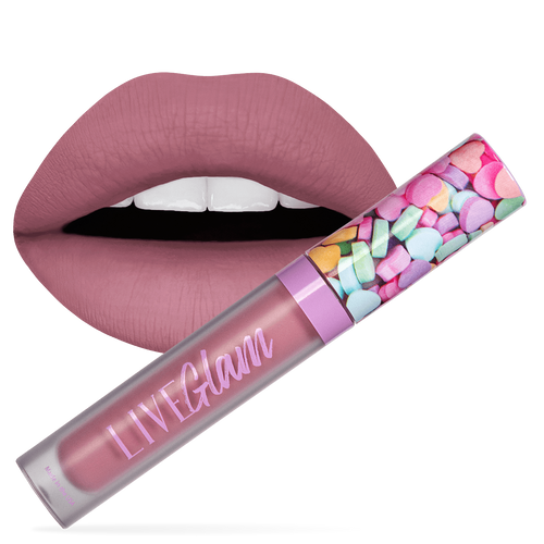 A close-up image of a person's lips wearing the matte Kiss Me pearly purple lipstick, with a bottle of the LiveGlam the Kiss Me liquid lippie in front. The Kiss Me bottle features a cap with a valentine candy heart design.